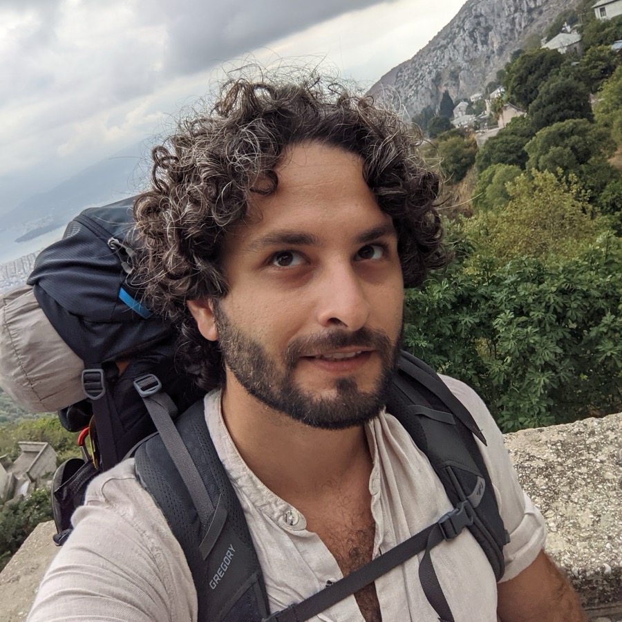 Adam Etzion, with a backpack, on a mountain path above the sea